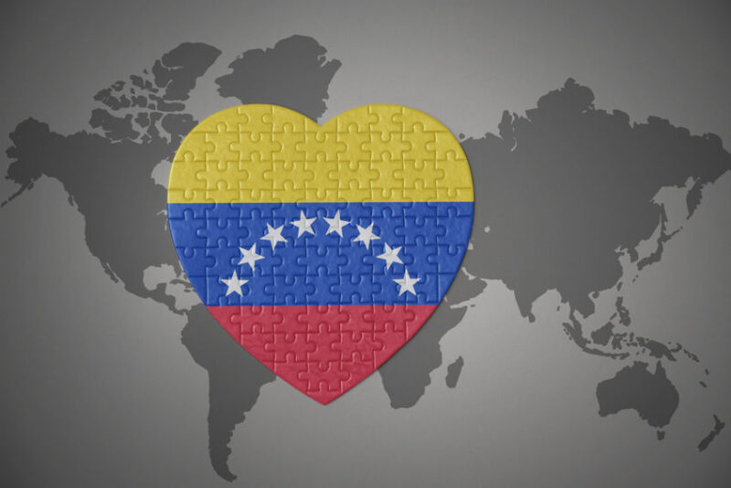 puzzle heart with the national flag of venezuela on a world map background.