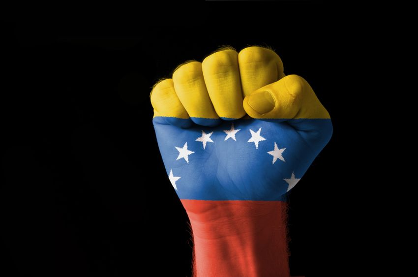 11112298 low key picture of a fist painted in colors of venezuela flag