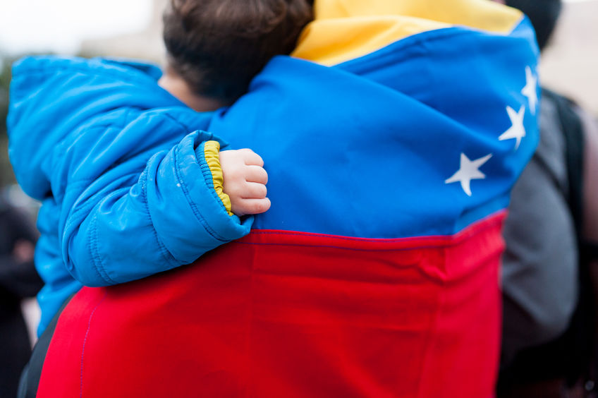 detail of little child hand on venezuelan flag as symbol of hope in future regime change, during march in support of Guaido government