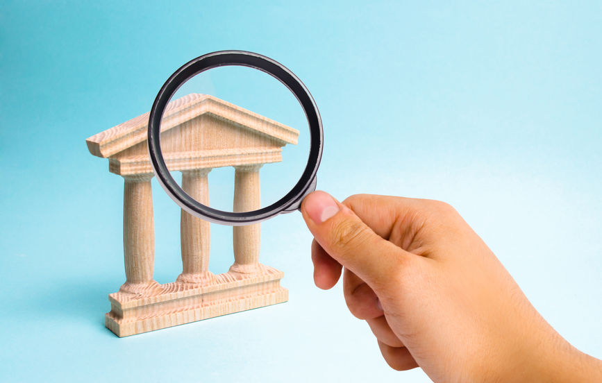 Magnifying glass is looking at the Wooden monument or government building. Minimalistic representation of a statebuilding , a courthouse or a monument of history, an ineptration of justice