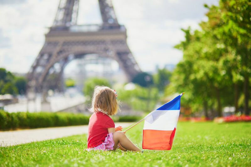 toddler girl with French national tricolor flag near the Eiffel tower in Paris, France