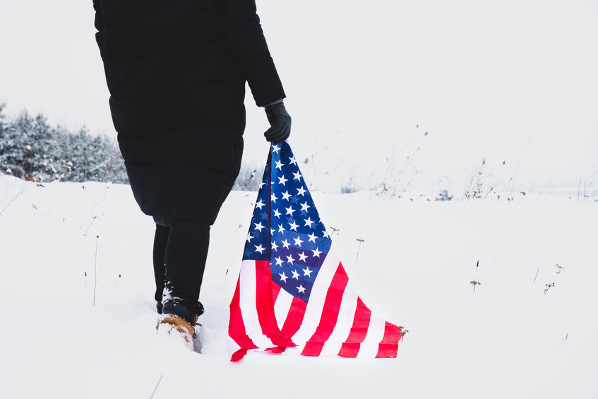 woman walk by snowed filed with usa flag in hands. close up