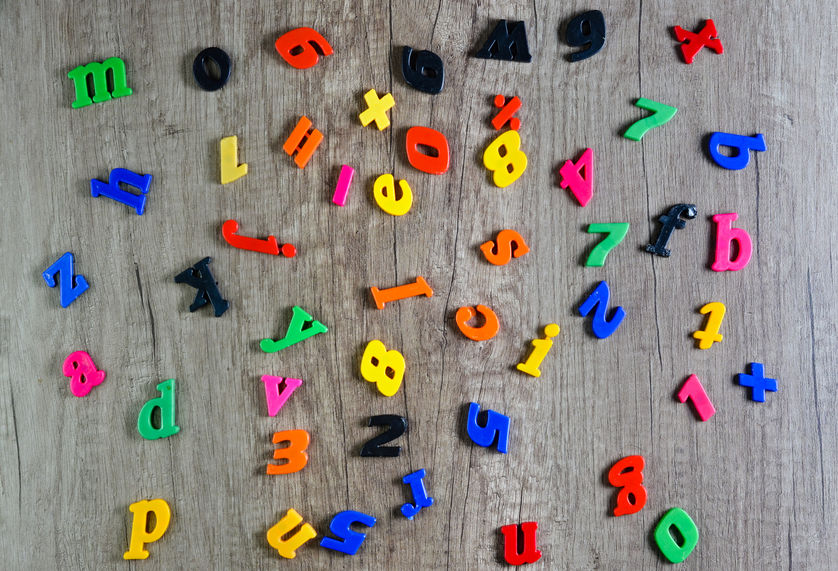 Directly above shot of multi colored plastic numbers and letters on wooden table .