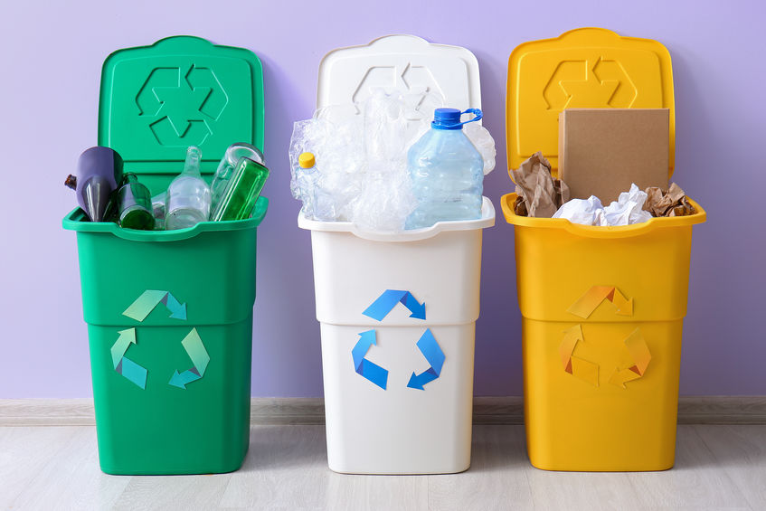 Containers with different types of garbage near lilac wall. Recycling concept